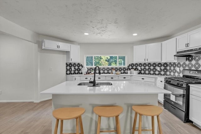 kitchen with white cabinetry, black range with gas stovetop, a breakfast bar area, and a center island with sink