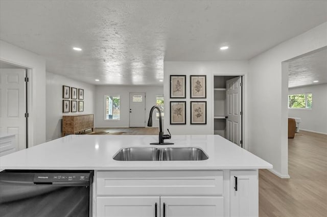 kitchen with a healthy amount of sunlight, black dishwasher, sink, and white cabinets