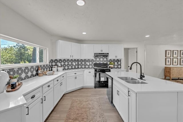 kitchen featuring sink, gas stove, white cabinetry, a center island with sink, and dishwasher