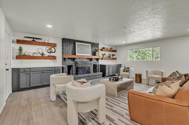 living room with light hardwood / wood-style flooring, a fireplace, and a textured ceiling