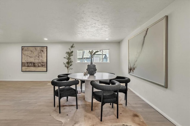 dining space with hardwood / wood-style floors and a textured ceiling