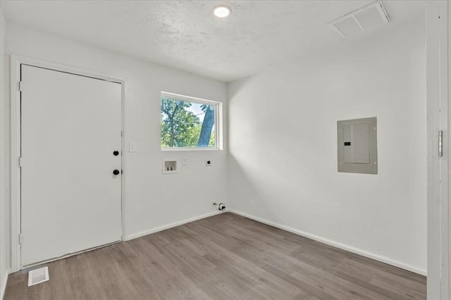 clothes washing area featuring electric panel, hookup for a washing machine, electric dryer hookup, hardwood / wood-style flooring, and hookup for a gas dryer