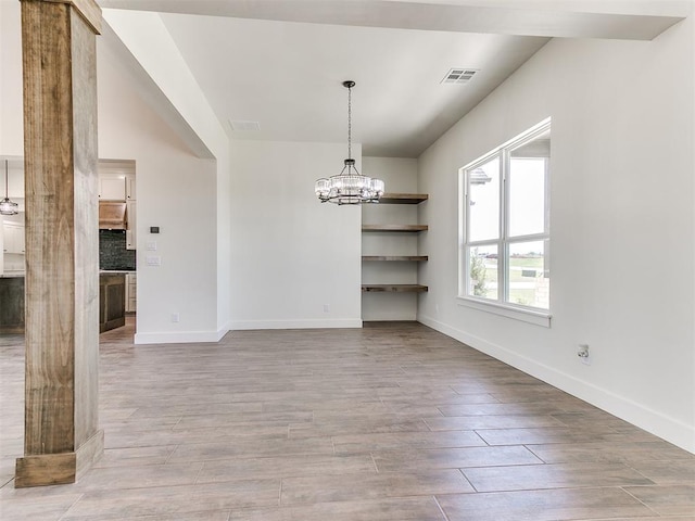 unfurnished dining area with a chandelier, baseboards, visible vents, and wood finished floors