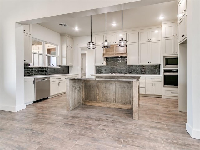 kitchen featuring white cabinets, premium range hood, a center island, stainless steel appliances, and backsplash