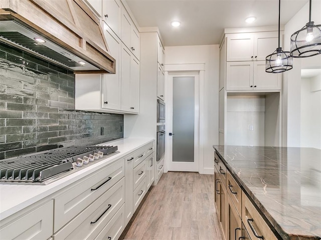 kitchen with premium range hood, white cabinetry, light wood-type flooring, stainless steel gas stovetop, and tasteful backsplash