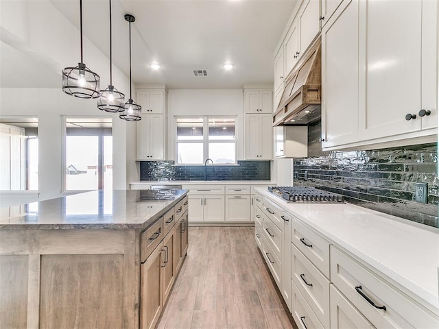 kitchen featuring decorative backsplash, visible vents, stainless steel gas cooktop, light wood-type flooring, and under cabinet range hood