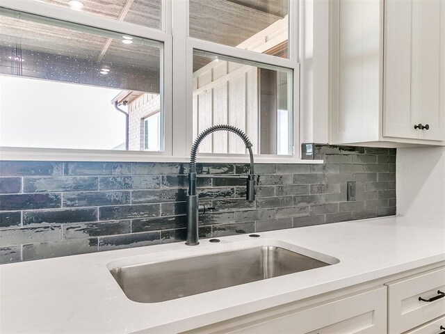 kitchen with a sink, light countertops, tasteful backsplash, and white cabinets