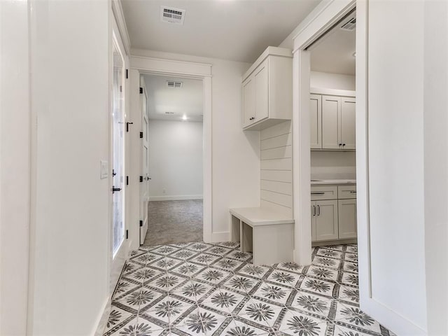 mudroom featuring visible vents, baseboards, and light colored carpet