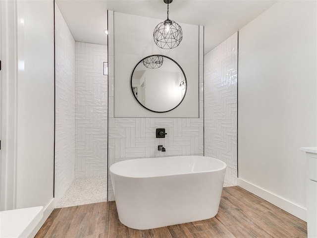 full bath with a walk in shower, a freestanding bath, and wood finished floors
