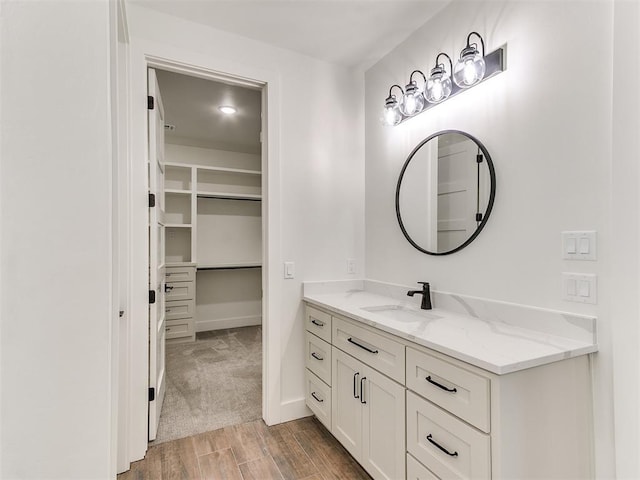 bathroom with vanity, baseboards, wood finished floors, and a spacious closet
