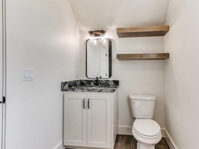 bathroom featuring vanity, baseboards, wood finished floors, and toilet