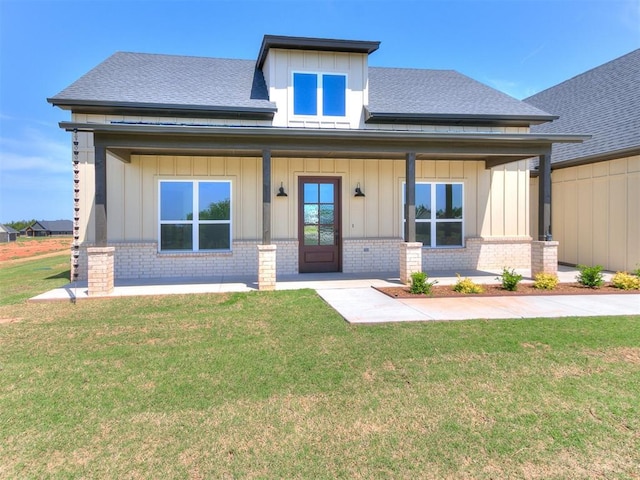 view of front of property featuring board and batten siding, a front yard, and brick siding