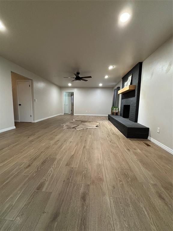 unfurnished living room with ceiling fan, a fireplace, and hardwood / wood-style floors