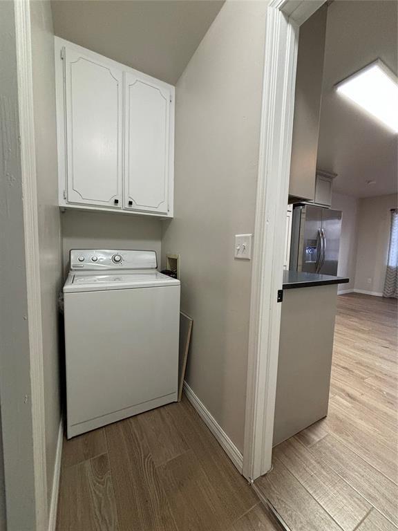 washroom featuring washer / clothes dryer, cabinets, and light hardwood / wood-style floors