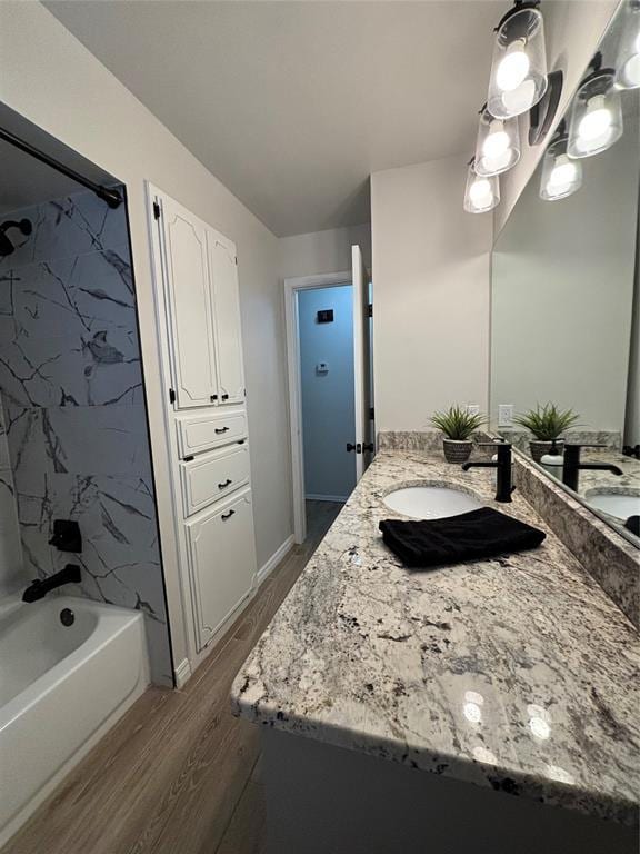 bathroom featuring hardwood / wood-style flooring, vanity, and tiled shower / bath combo