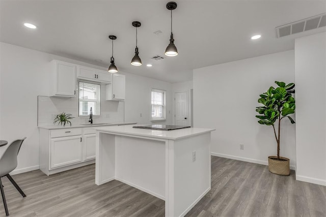 1617 NW 31st St, Oklahoma City, OK 73118 - kitchen with sink, white cabinetry, light hardwood / wood-style floors, a kitchen island, and decorative light fixtures