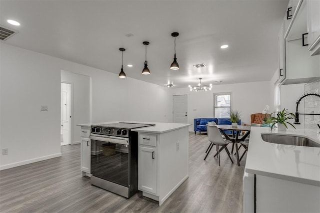 1617 NW 31st St, Oklahoma City, OK 73118 - kitchen featuring sink, decorative light fixtures, a center island with sink, electric stove, and white cabinets