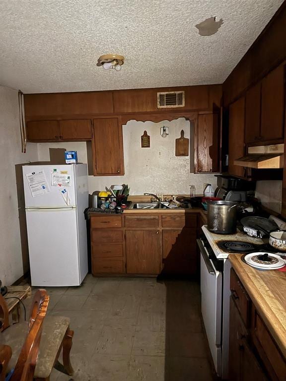 kitchen with sink, a textured ceiling, and white appliances