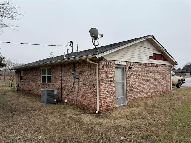 back of property with a yard and central AC