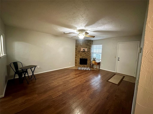 unfurnished living room featuring dark hardwood / wood-style floors, a textured ceiling, a fireplace, and ceiling fan