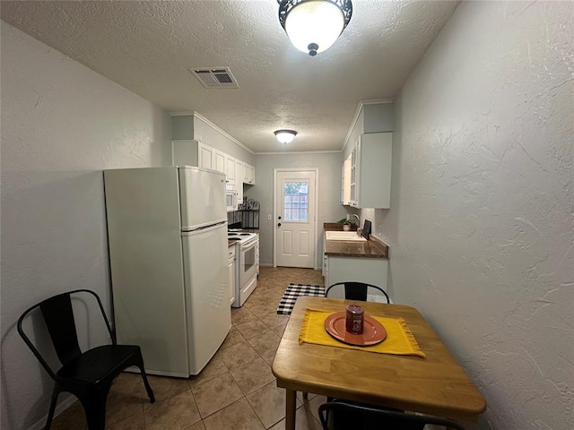 7191 NW 16th St, Bethany, OK 73008 - kitchen with white appliances, light tile patterned floors, a textured ceiling, and white cabinets
