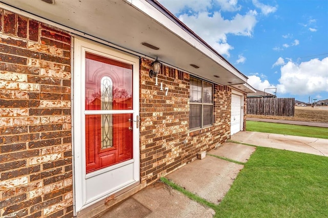 entrance to property featuring a yard and a garage