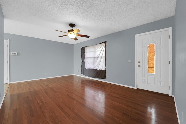 interior space featuring ceiling fan, dark wood-type flooring, and a textured ceiling