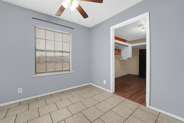 empty room featuring light tile patterned flooring, ceiling fan, and a textured ceiling