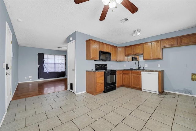 kitchen featuring sink, light tile patterned floors, a textured ceiling, and black appliances