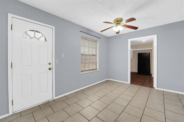 foyer entrance featuring light tile patterned floors, a textured ceiling, and ceiling fan