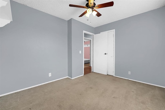 unfurnished bedroom featuring light carpet, ceiling fan, a closet, and a textured ceiling