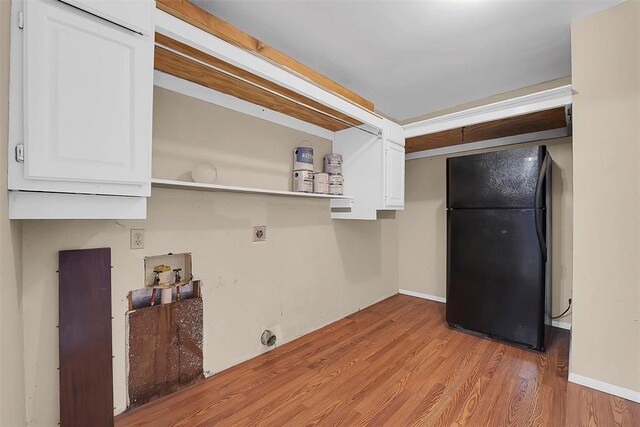 kitchen with white cabinetry, black fridge, and light hardwood / wood-style flooring