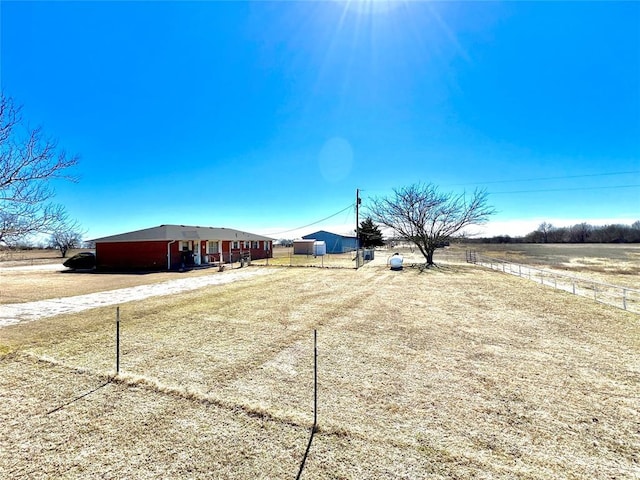 view of yard with an outbuilding, a rural view, an outdoor structure, and driveway