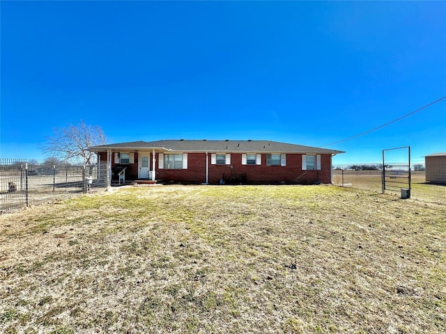 view of front of home with brick siding, a front yard, and fence