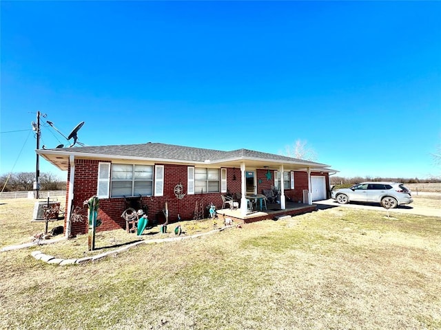 single story home with a front yard, concrete driveway, brick siding, and an attached garage