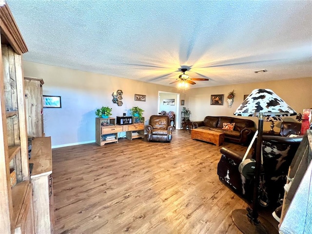 living room featuring ceiling fan, a textured ceiling, light wood-type flooring, and visible vents