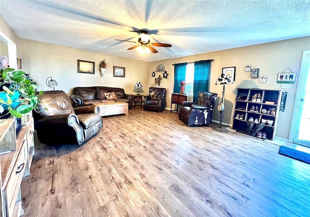 living area featuring baseboards, a textured ceiling, a ceiling fan, and wood finished floors