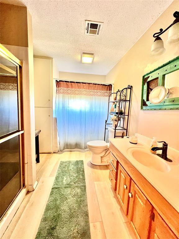 full bath with wood finished floors, a shower with door, and visible vents