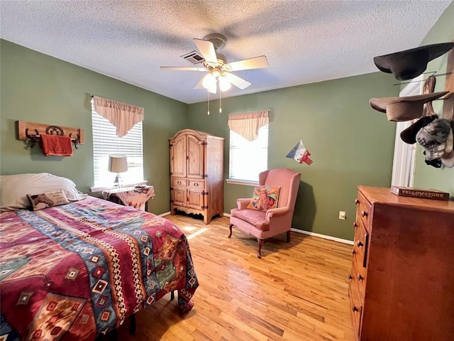 bedroom with light wood finished floors, baseboards, visible vents, ceiling fan, and a textured ceiling