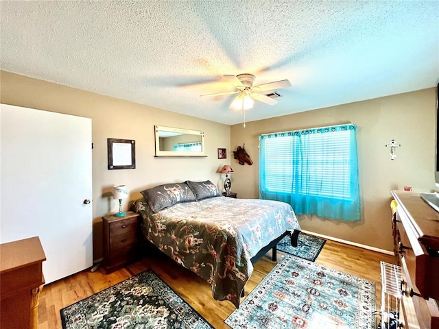 bedroom featuring a ceiling fan, a textured ceiling, and wood finished floors