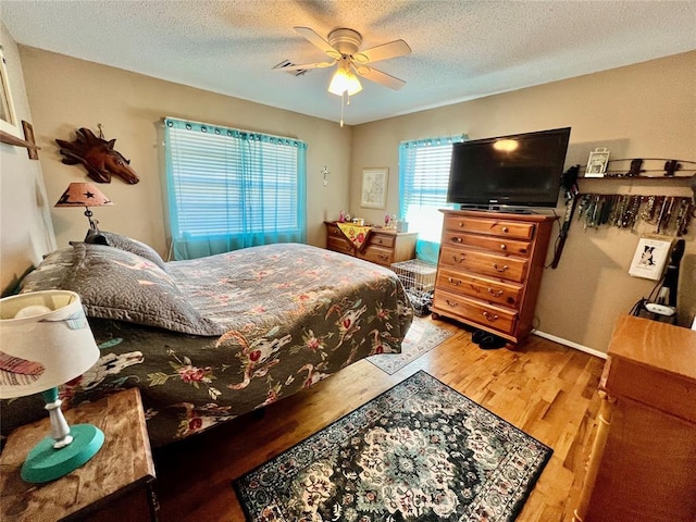 bedroom featuring a textured ceiling, ceiling fan, and wood finished floors