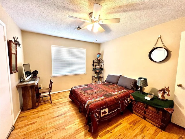 bedroom featuring a textured ceiling, wood finished floors, visible vents, and a ceiling fan