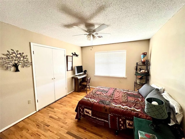 bedroom featuring a textured ceiling, ceiling fan, a closet, and wood finished floors