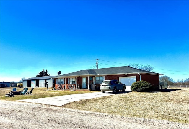 single story home featuring a garage, brick siding, driveway, and a front lawn