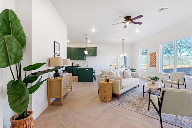 living room with ceiling fan with notable chandelier, visible vents, baseboards, and recessed lighting