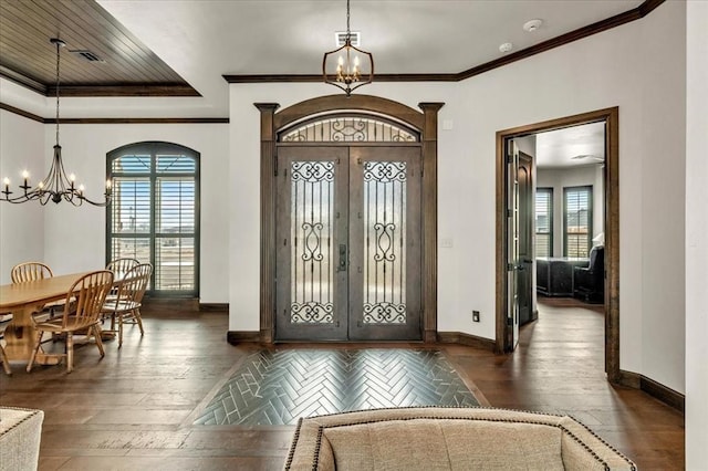 entrance foyer with a notable chandelier, dark hardwood / wood-style floors, ornamental molding, and french doors