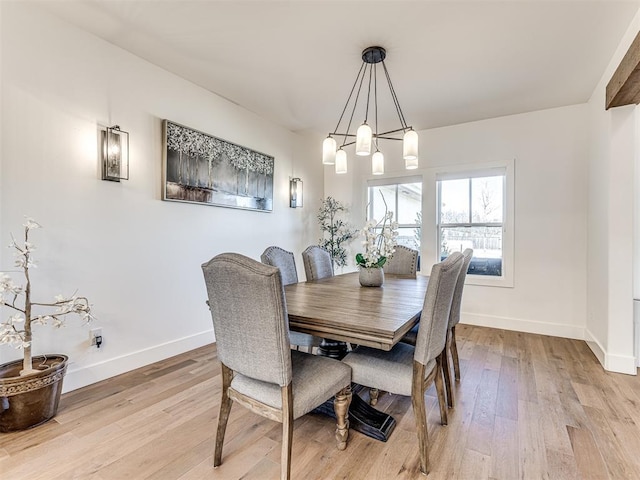 dining area with a notable chandelier, light wood-style flooring, and baseboards