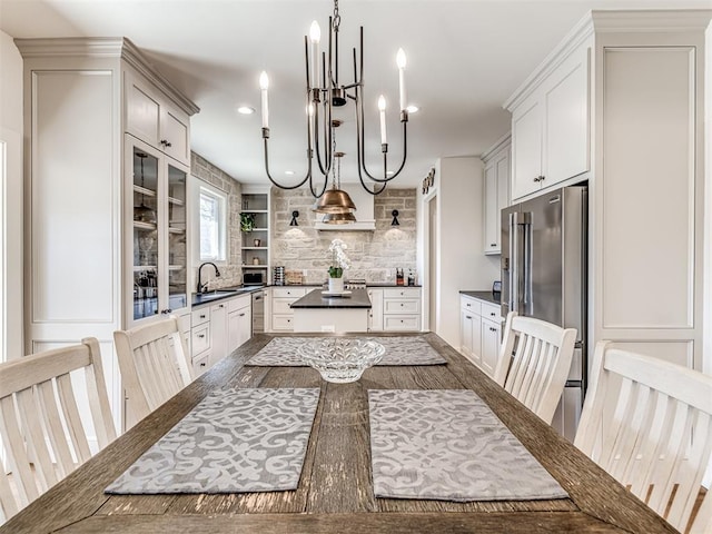 kitchen with open shelves, dark countertops, hanging light fixtures, high quality fridge, and a sink