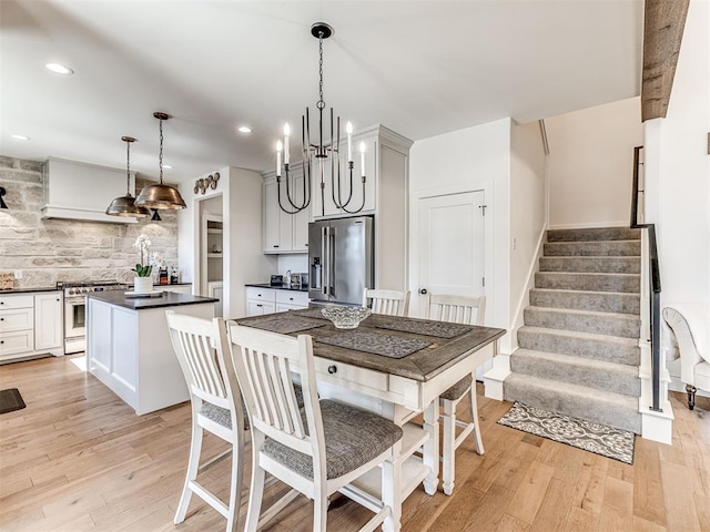 dining space with light wood-type flooring, an inviting chandelier, stairway, and recessed lighting