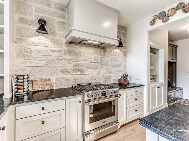 kitchen featuring stainless steel gas stove, tasteful backsplash, custom range hood, and white cabinets